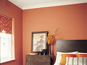 Orange bedroom with white ceiling and dark wooden furniture white bedding orange pillows